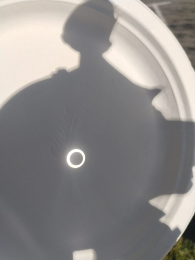 shadow of a telescope with a circle of light from the sun with a shadow of the moon in the center